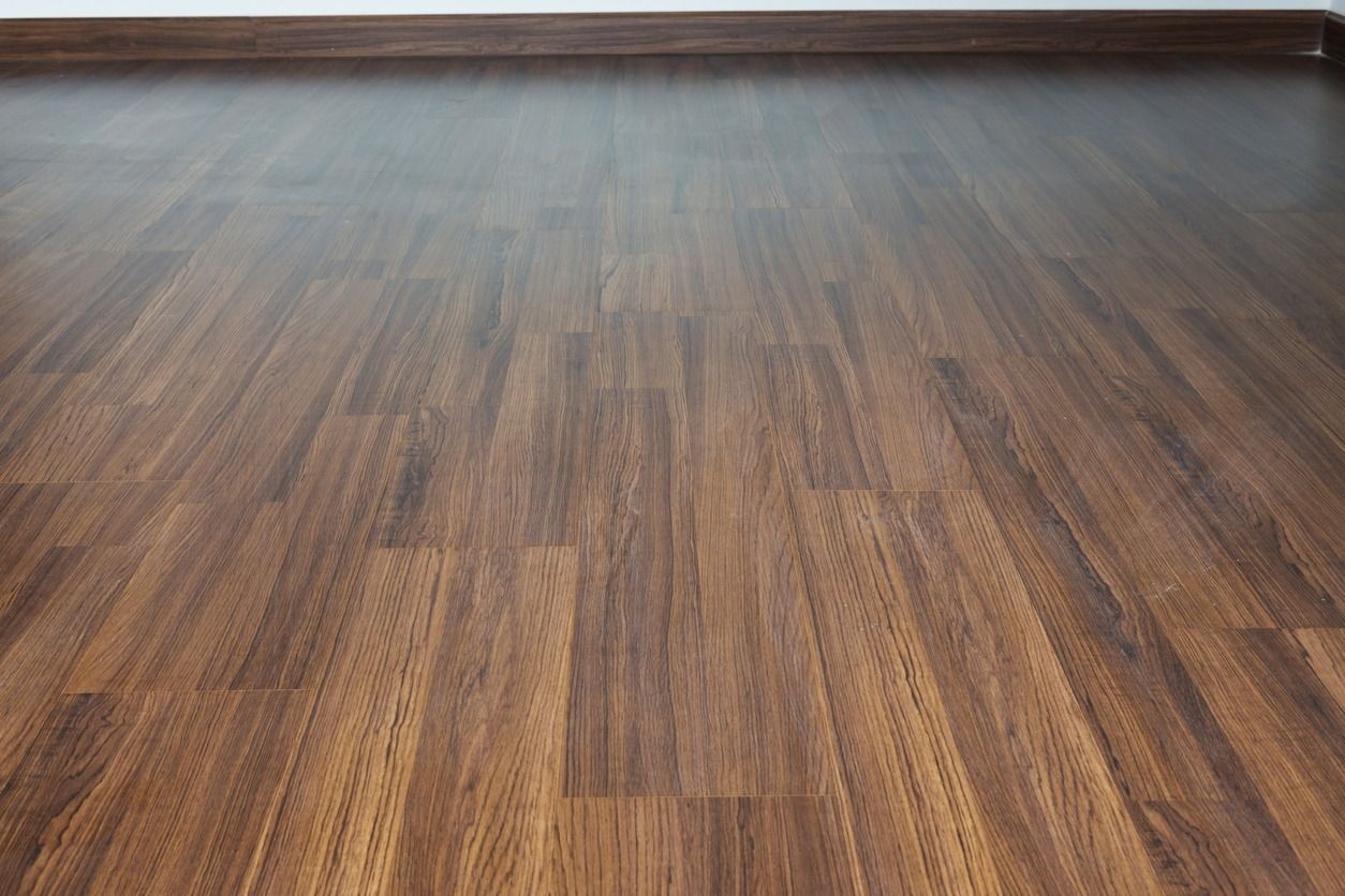 Piso de madera oscura que conduce hacia una pared clara con un borde marrón en la parte superior.