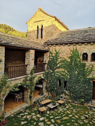 Un gran edificio de piedra con un patio delante.
