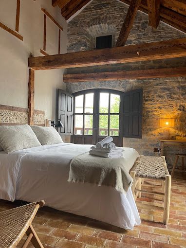 Un dormitorio con una cama, sillas y una ventana.