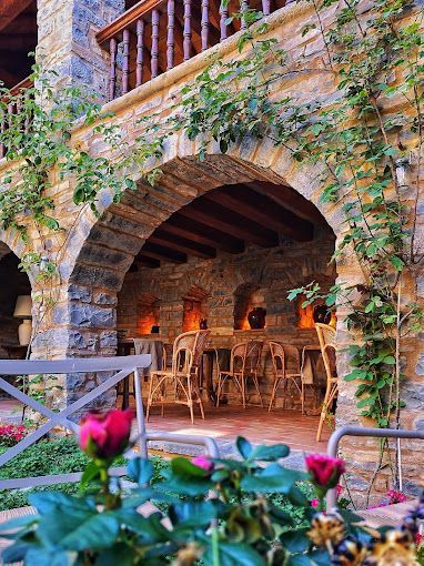 Un arco de piedra que conduce a un restaurante con mesas y sillas.