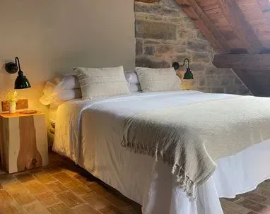 Un dormitorio con una cama grande y una pared de piedra.