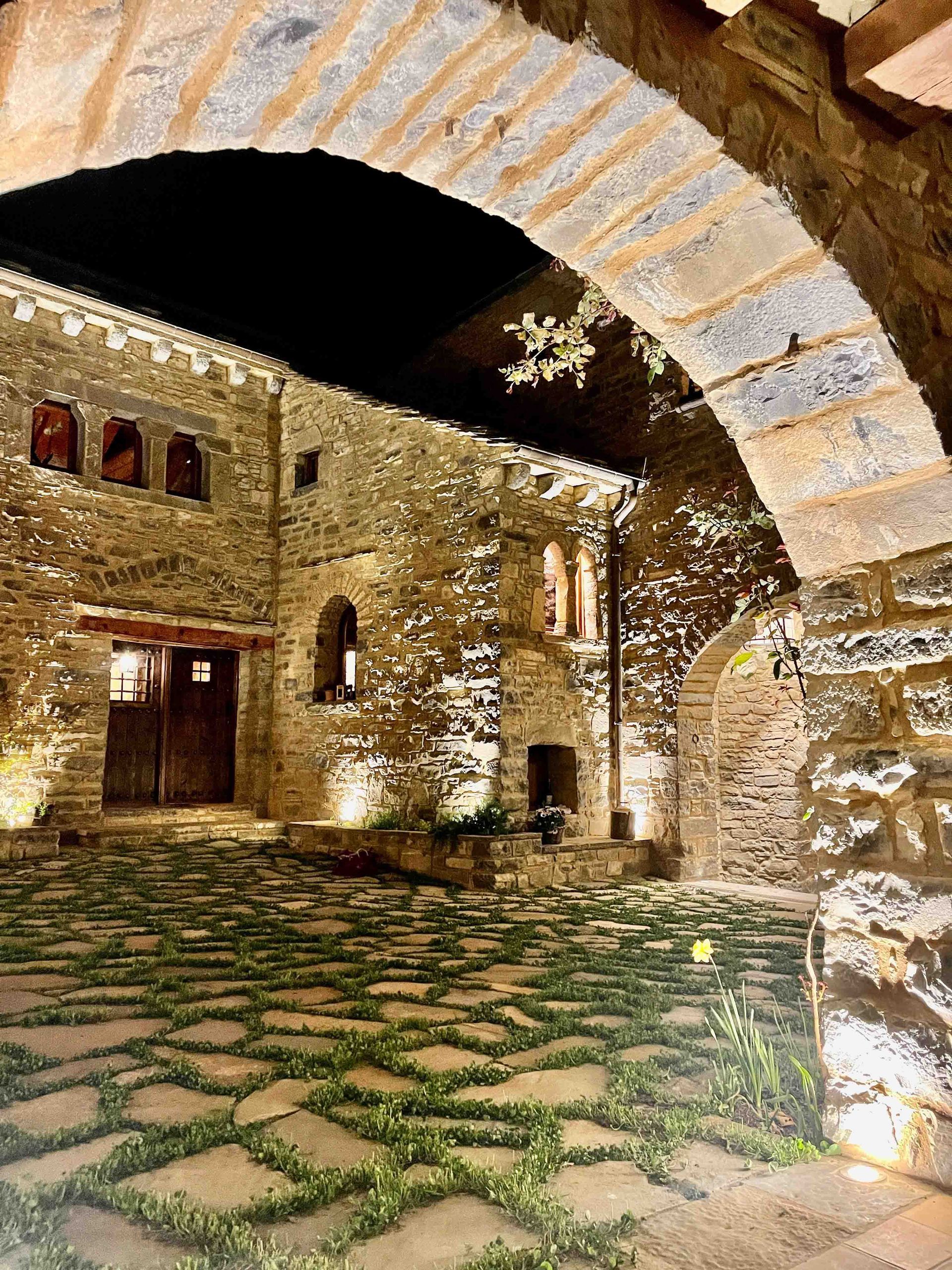 Un edificio de piedra con una pasarela de piedra delante de él por la noche.