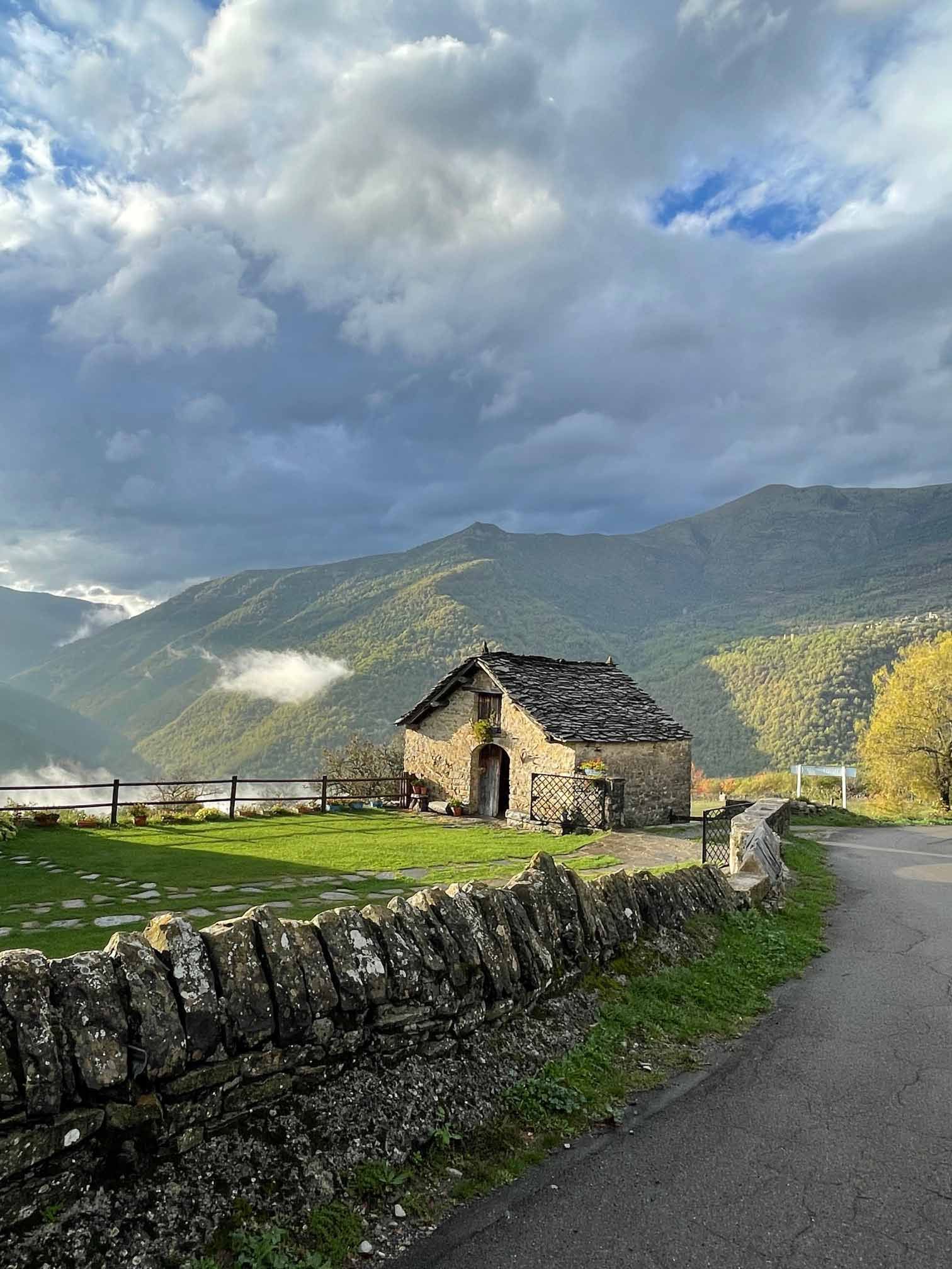 Una pequeña casa está situada al costado de una carretera en las montañas.