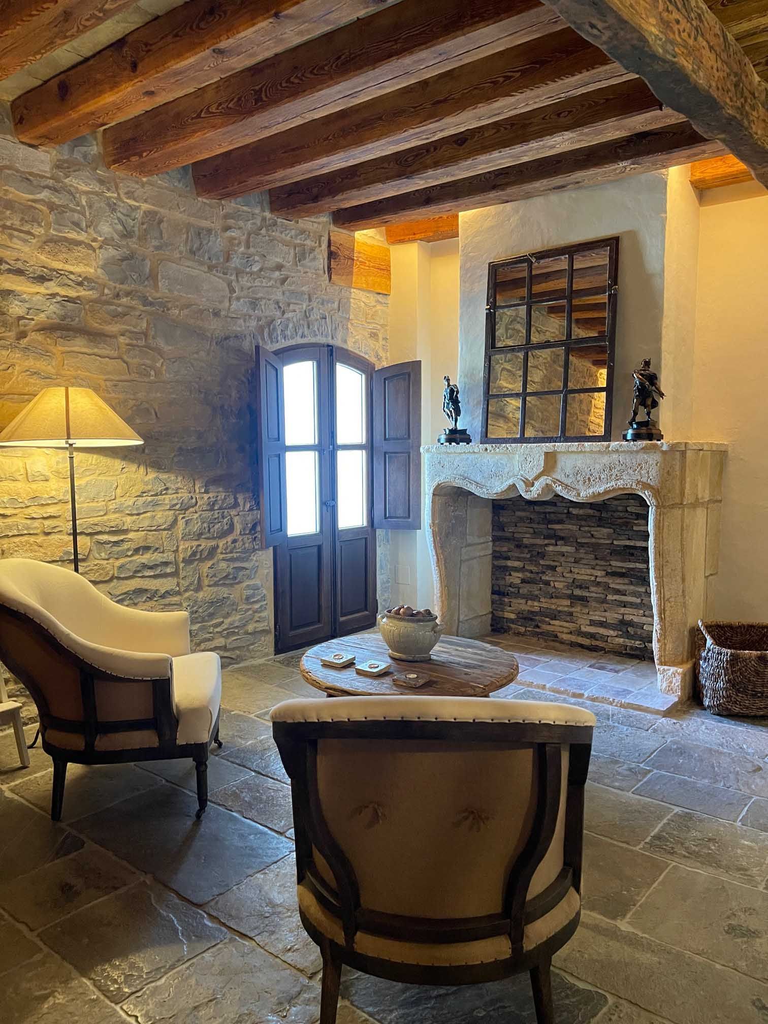 Una sala de estar con chimenea, sillas, una mesa y una lámpara.