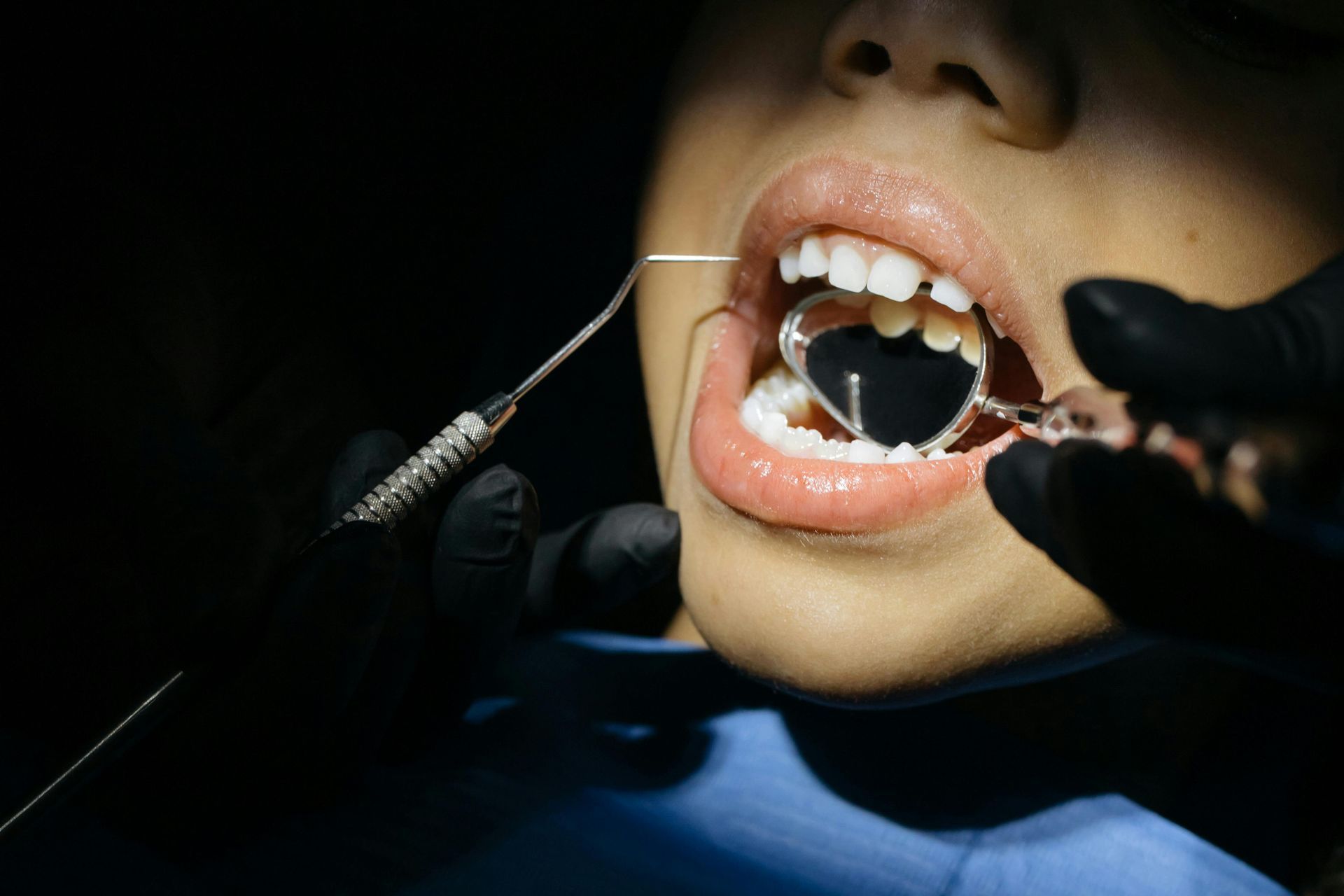 Dentista examinando os dentes de um paciente com instrumentos odontológicos em um consultório odontológico bem iluminado.