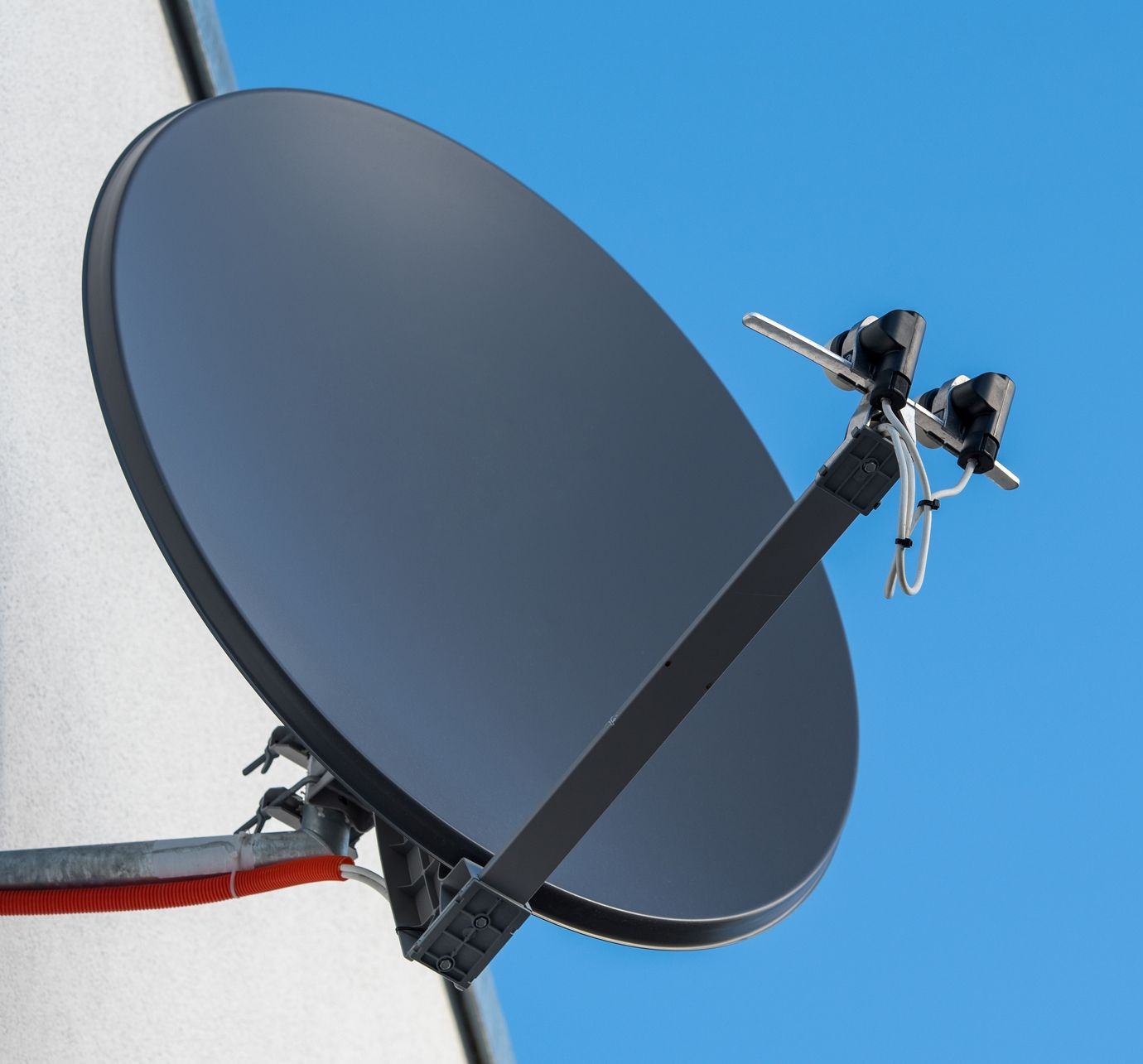 Une antenne parabolique avec deux récepteurs LNB fixée à un mur.