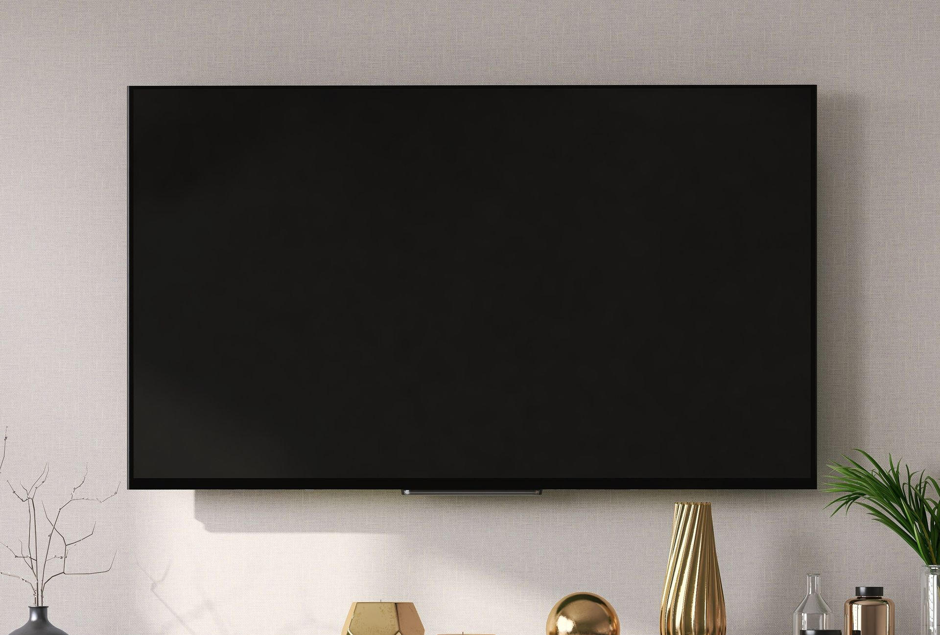 Un écran de télévision rectangulaire et vierge, fixé à un mur clair et texturé, au-dessus d'une étagère garnie d'objets décoratifs.