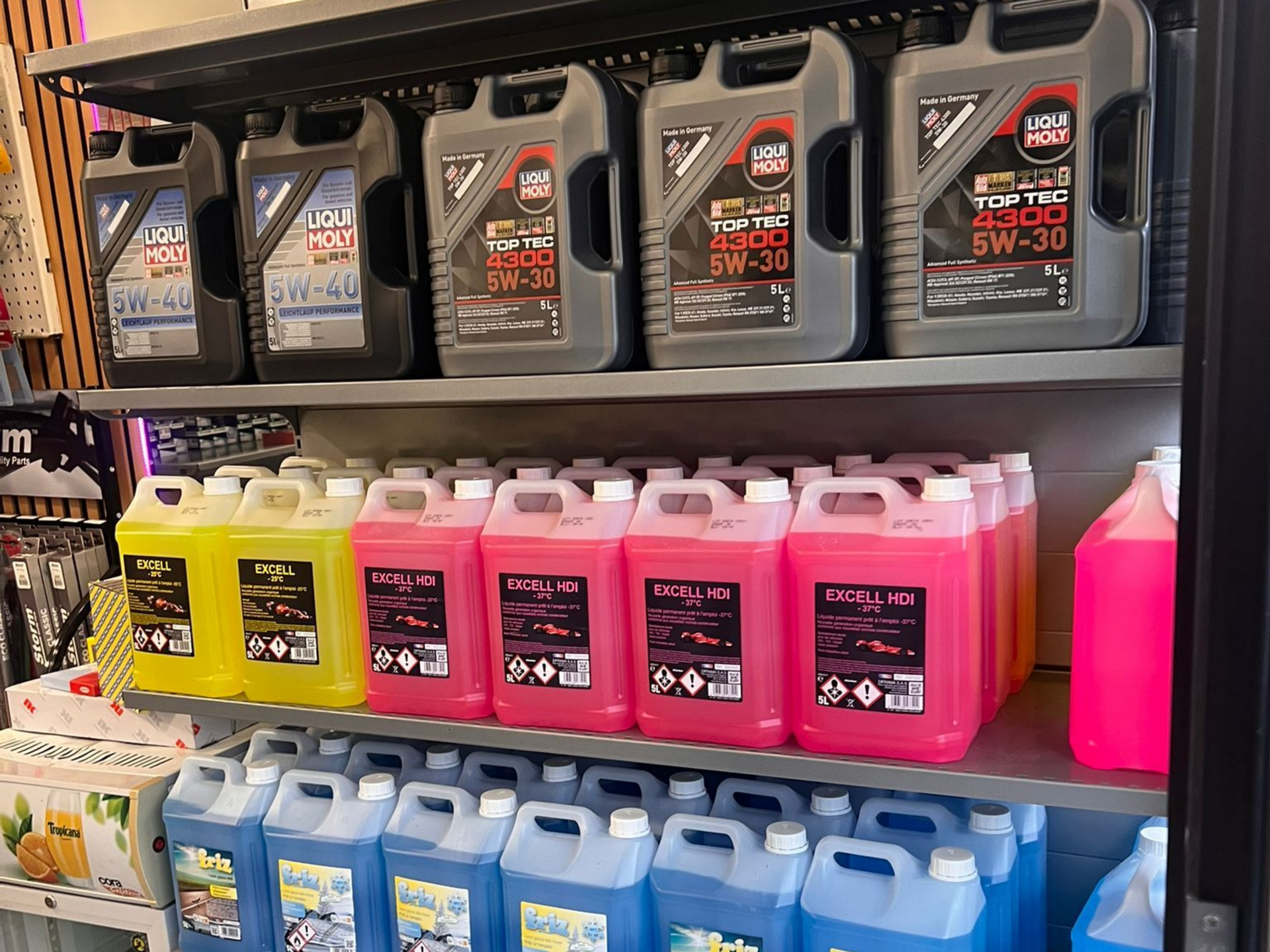 Des étagères remplies d'huile à moteur et de liquides de différentes couleurs : gris, jaune, rose et bleu.