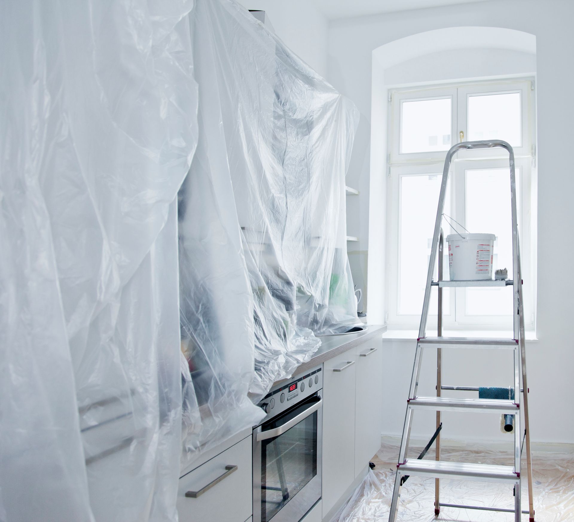 Cuisine recouverte de plastique pour la peinture, échelle à côté de la fenêtre.