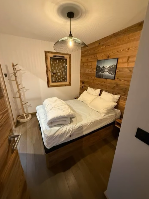 Chambre confortable avec mur d'accent en bois, lit avec literie blanche et suspension.