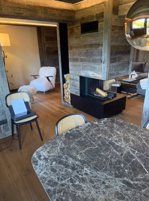 Un salon confortable avec une cheminée en pierre, des boiseries et une table avec plateau en marbre.