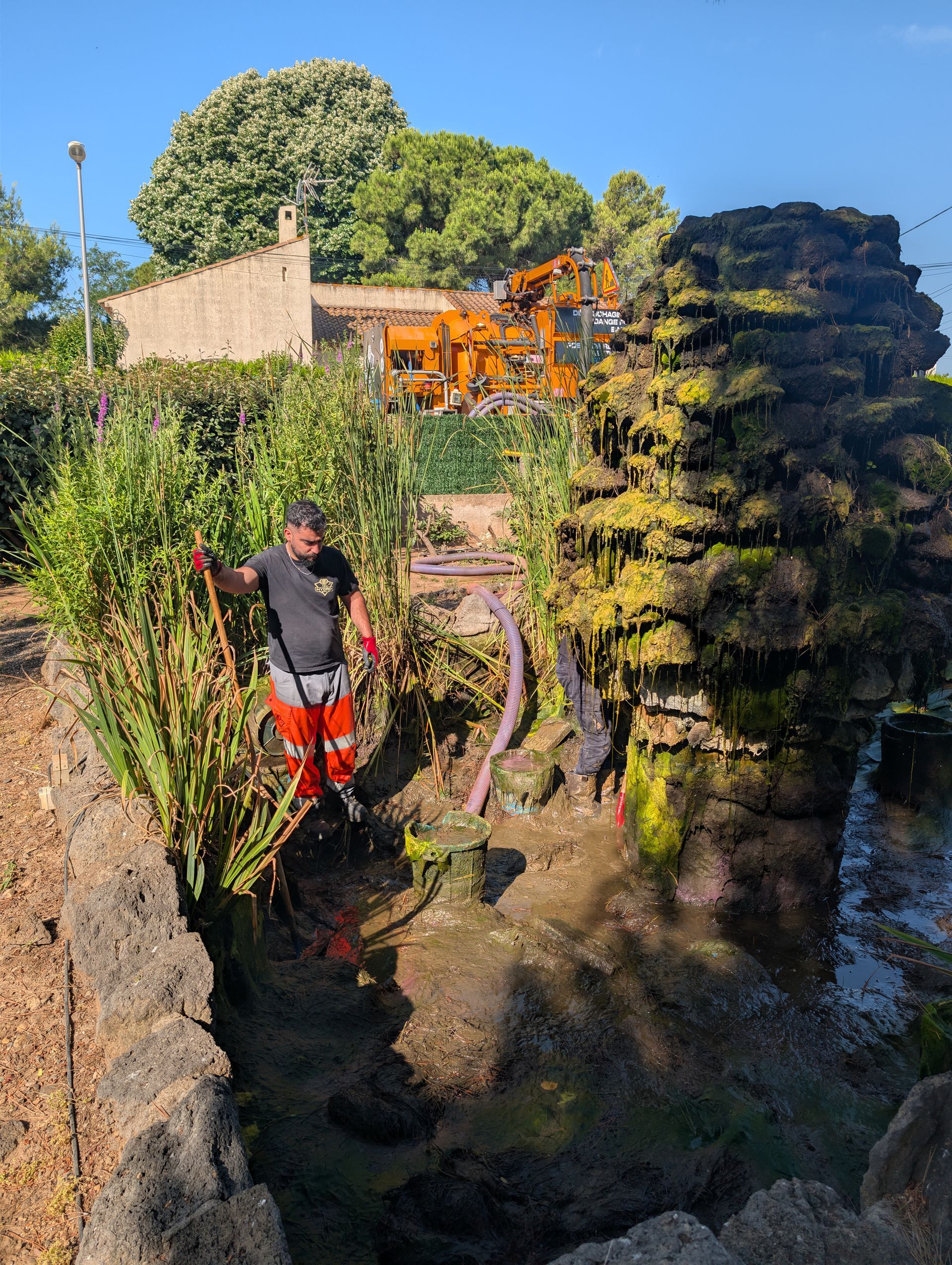 Une personne se tient debout dans un bassin d'orage afin de le nettoyer