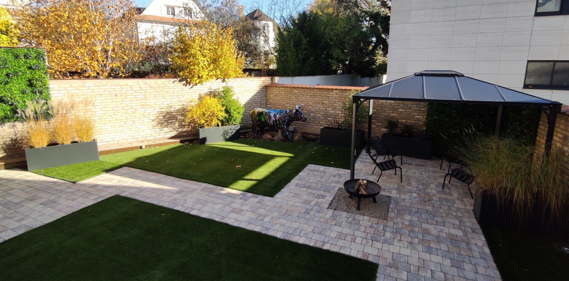 Cour arrière avec terrasse, pelouse et gazebo. Feuilles d'automne et verdure entourent l'espace.