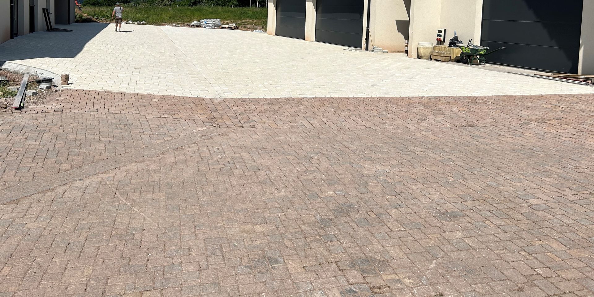 Allée en deux parties : pavés de briques au premier plan, gravier en arrière-plan, avec bâtiments.