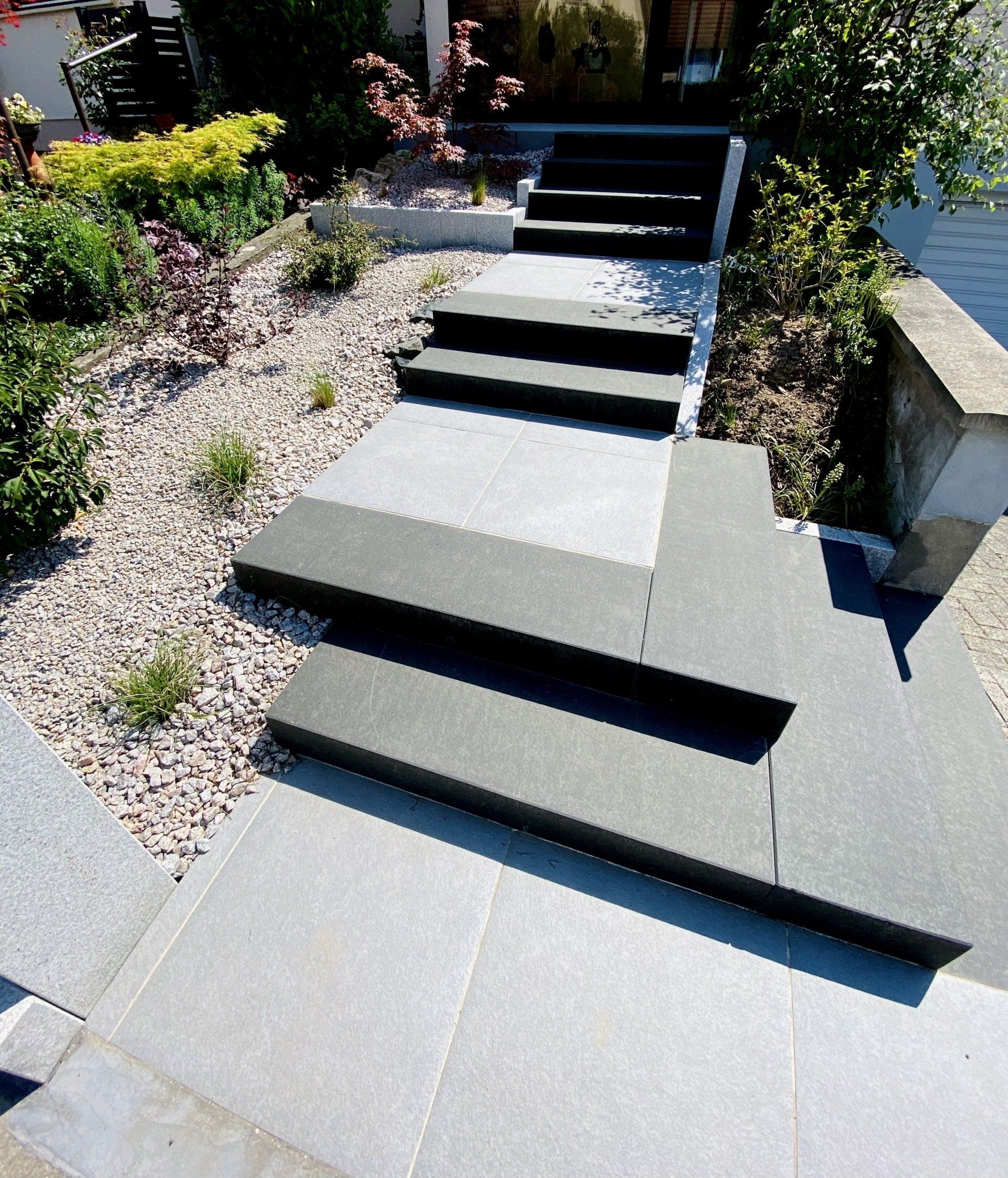 Des marches en pierre mènent à un chemin de jardin paysager.