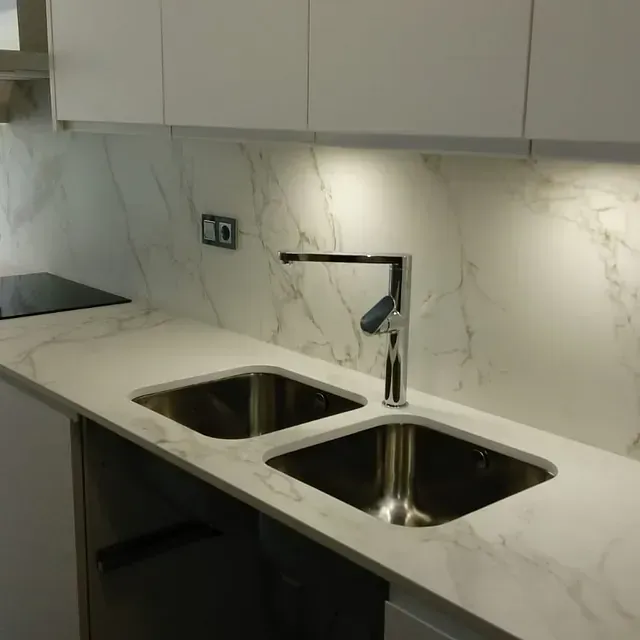 Una cocina con dos fregaderos y un grifo