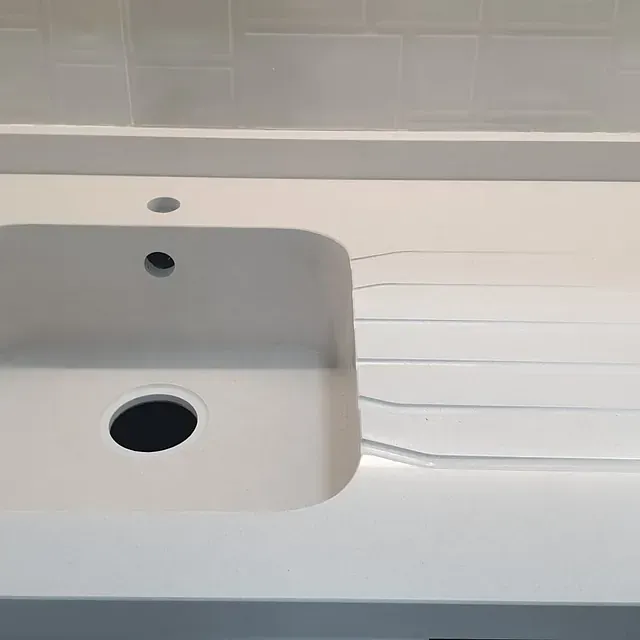 Un fregadero de cocina blanco con un agujero en el medio.