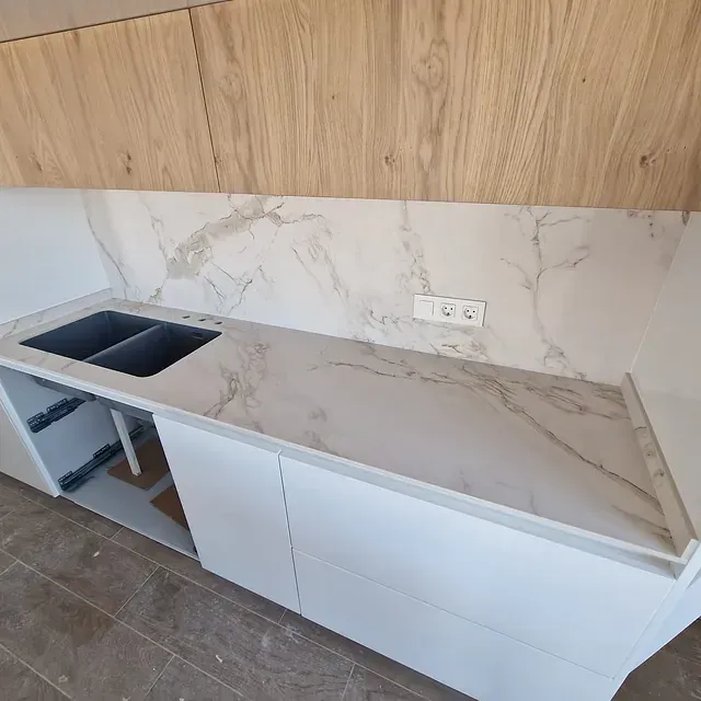 Una cocina con encimera de mármol y dos fregaderos.
