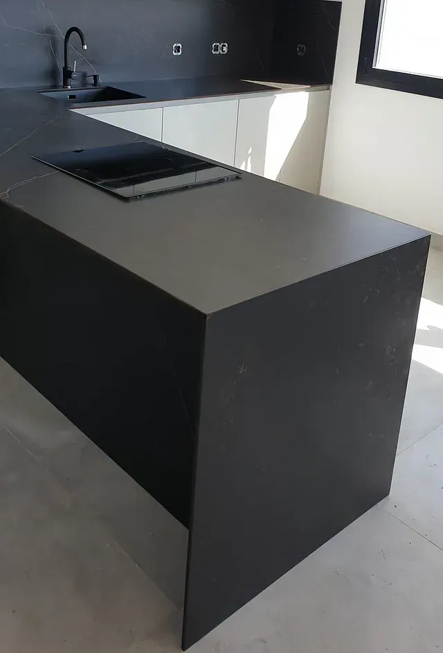 Una cocina con encimera negra y gabinetes blancos.