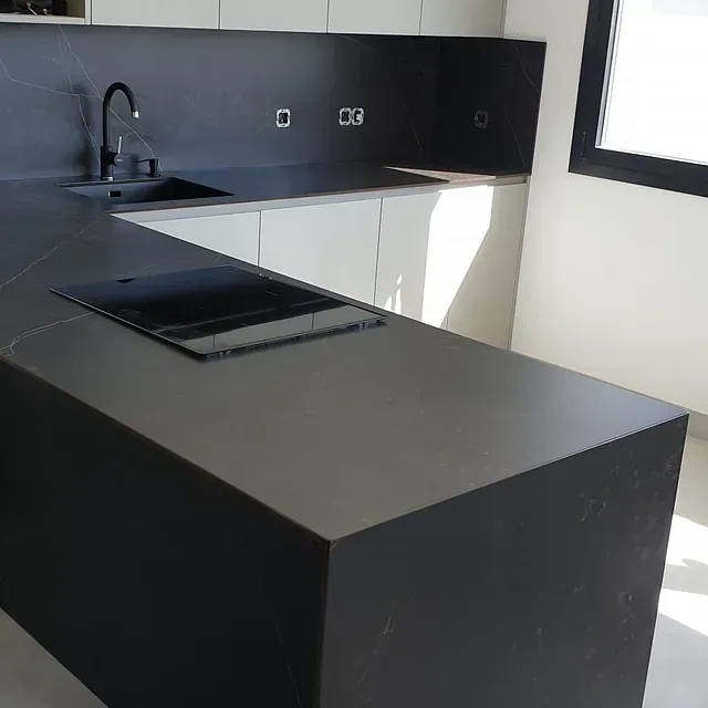 Una cocina con encimera negra y gabinetes blancos.