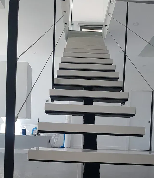 Una escalera con escalones blancos y barandilla negra.
