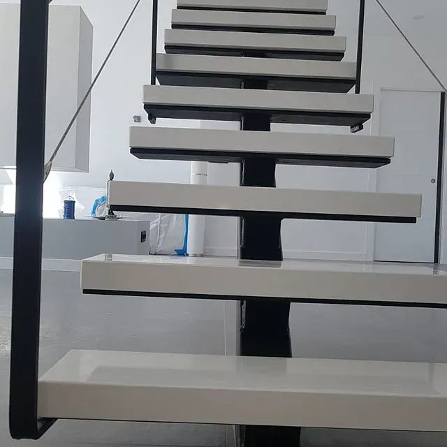 Una escalera con escalones blancos y barandilla negra.