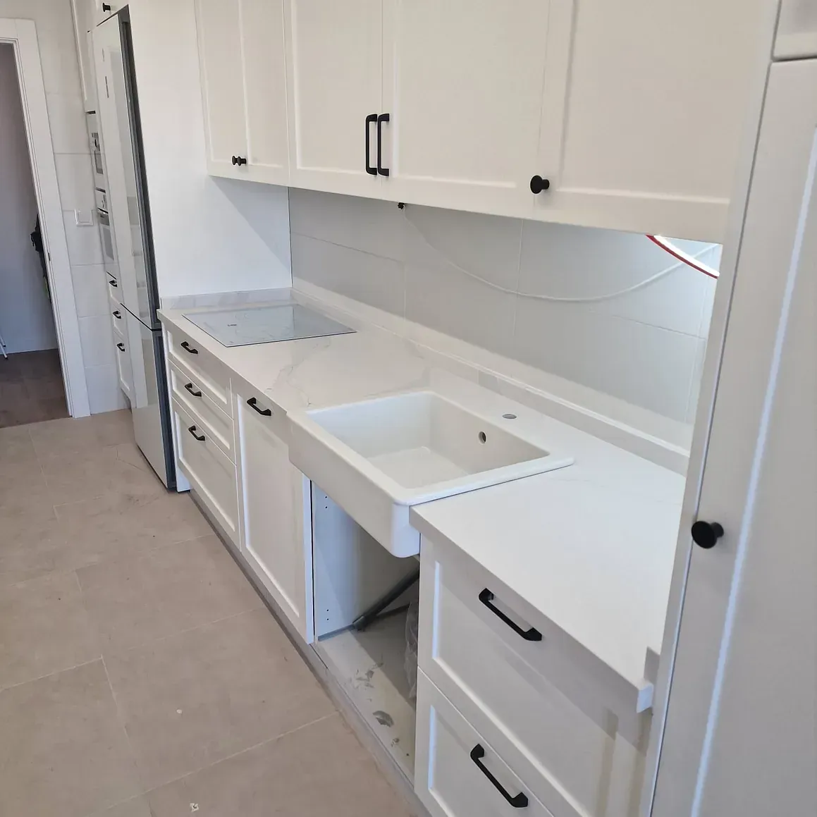 Una cocina con gabinetes blancos y un fregadero.
