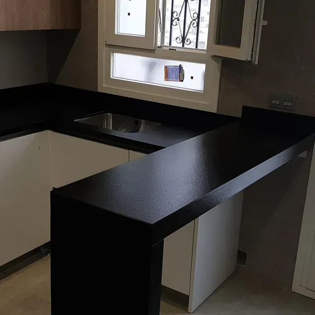 Una cocina con encimeras negras y gabinetes blancos.