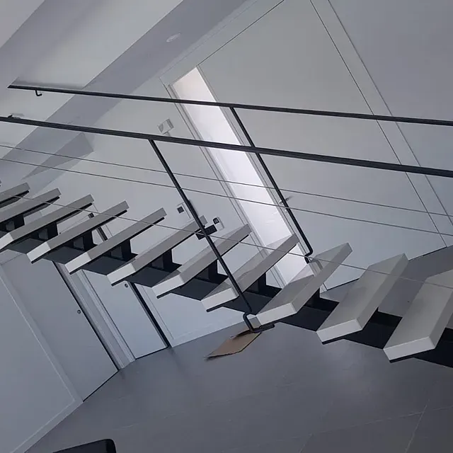 Una escalera con escalones blancos y barandilla negra.
