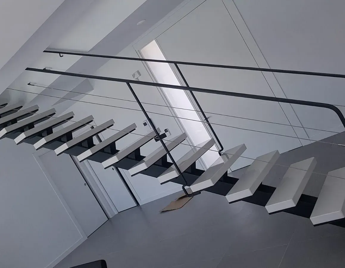 Una escalera con escalones blancos y barandilla negra.