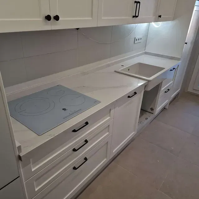 Una cocina con gabinetes blancos y un horno de estufa azul.