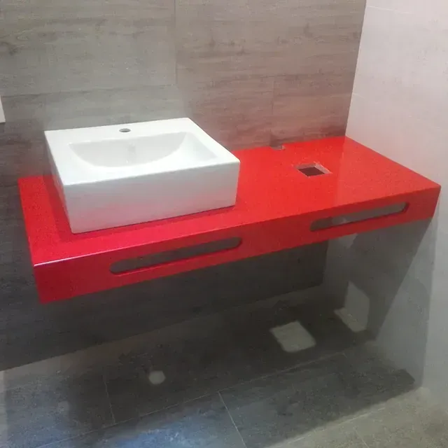 Un baño con encimera roja y lavabo blanco.