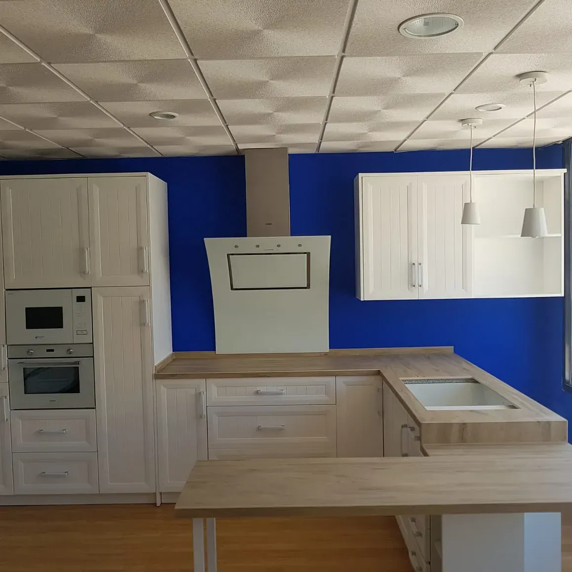 Una cocina con paredes azules y gabinetes blancos.