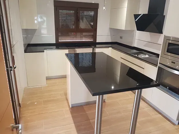 Una cocina con gabinetes blancos, un fregadero y un refrigerador.