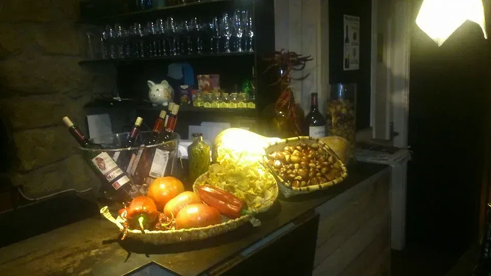 Una botella de vino reposa sobre un mostrador junto a una cesta de fruta.