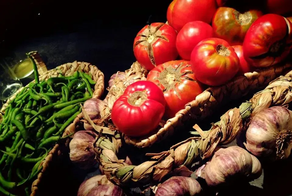 Un montón de verduras, incluyendo tomates, judías verdes y ajo.