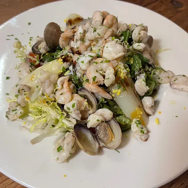 Un plato blanco cubierto con una ensalada de mariscos y verduras.
