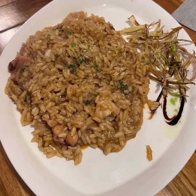 Un plato blanco cubierto con arroz y verduras sobre una mesa de madera.
