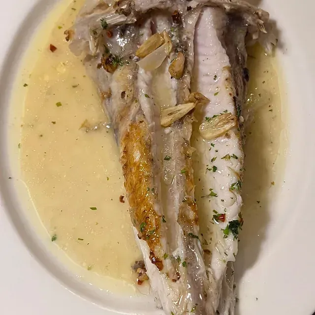 Un plato blanco cubierto con un trozo de pescado y salsa.