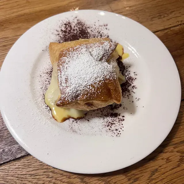 Un plato blanco cubierto con un trozo de masa y azúcar en polvo.