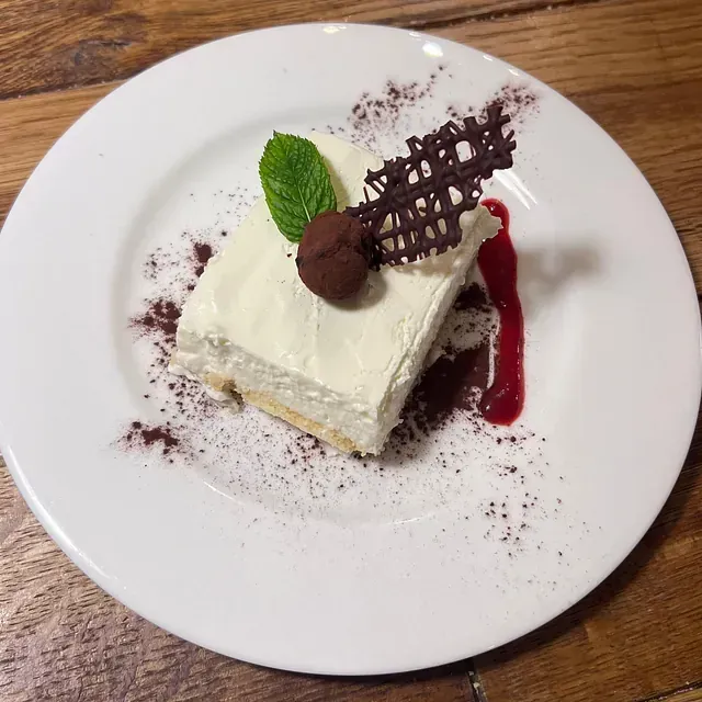 Un plato blanco cubierto con un trozo de pastel sobre una mesa de madera.