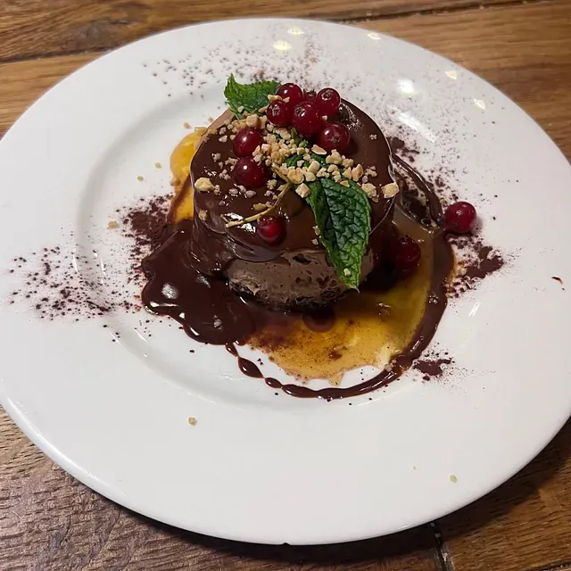 Un plato blanco cubierto con un postre de chocolate y bayas.