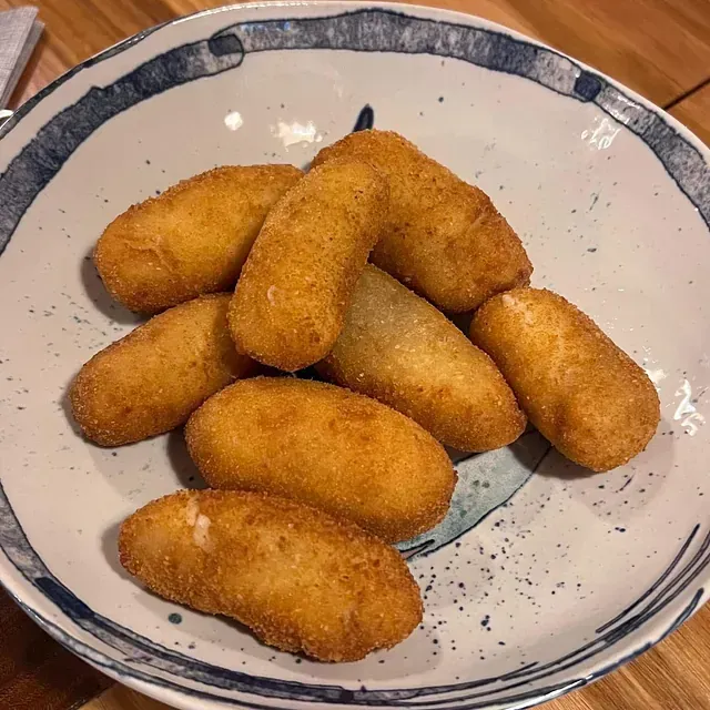 Un plato blanco cubierto con comida frita sobre una mesa de madera.