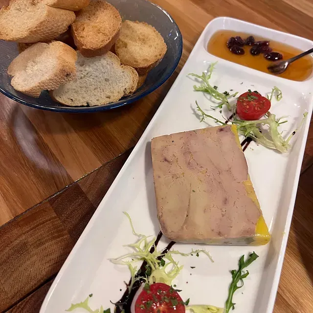 Un plato de comida con un trozo de foie gras encima.
