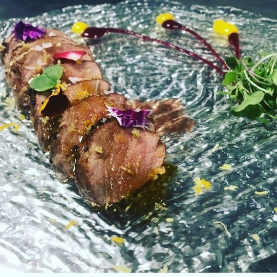Carne cortada en rodajas con guarnición en un plato de vidrio decorativo; fotografía cenital.