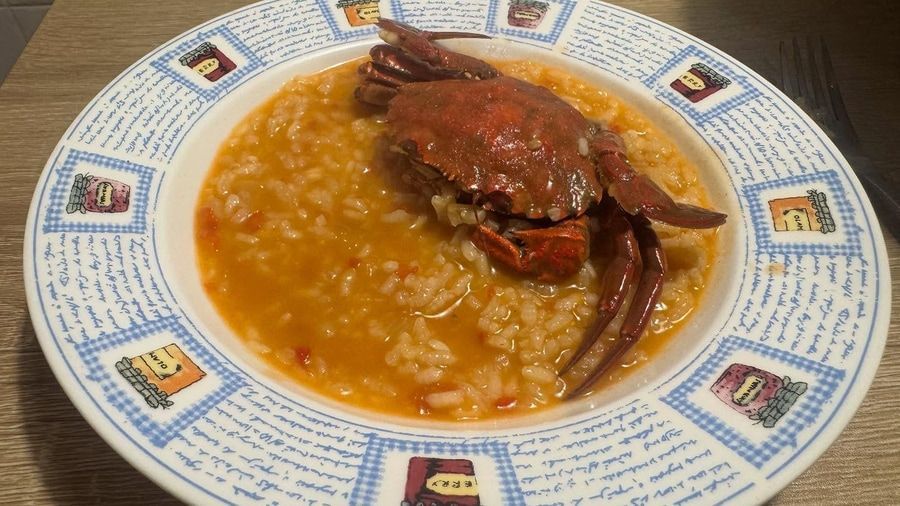 Guiso de cangrejo servido en un recipiente decorativo, cangrejo sobre arroz, guiso de naranja.