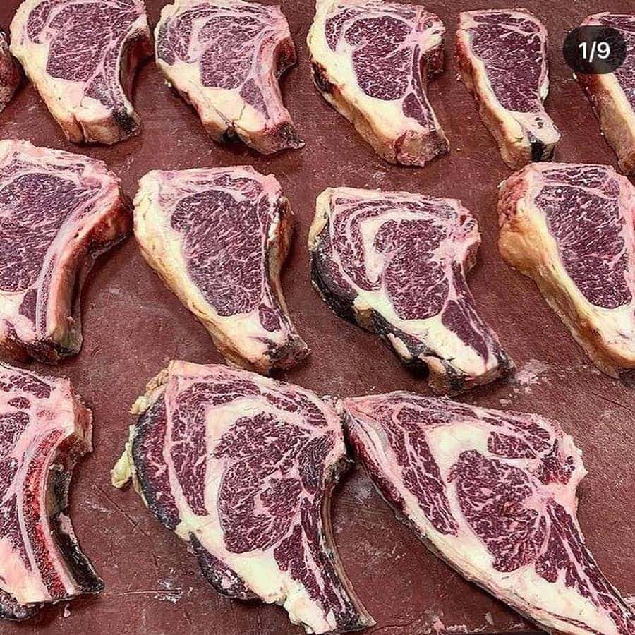 Filetes de costilla crudos y marmolados sobre una tabla de cortar roja, listos para cocinar.