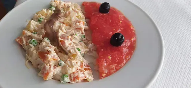 Un plato blanco cubierto con ensalada y salsa de tomate.