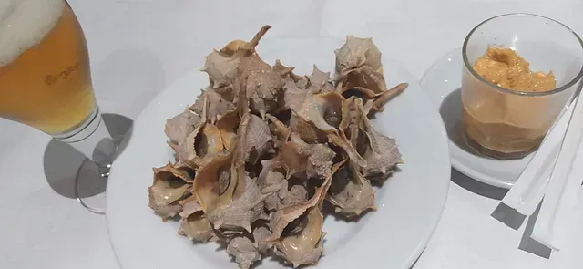 Un plato de comida y un vaso de cerveza en una mesa.