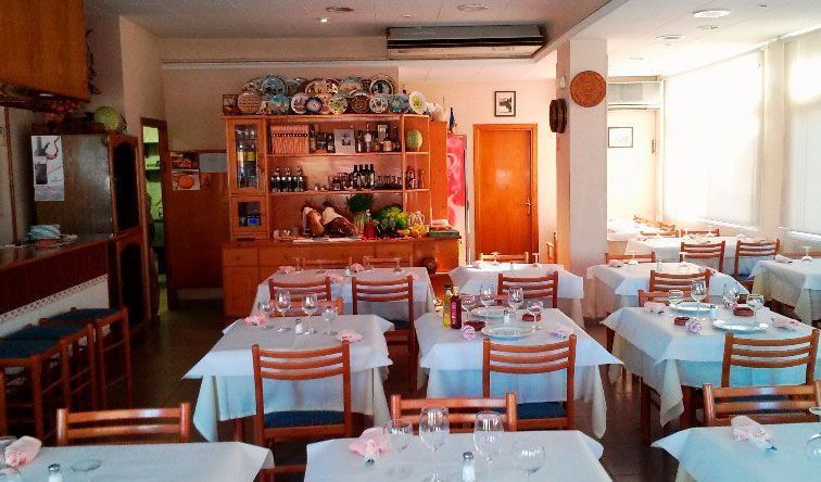 Un restaurante con mesas y sillas preparadas para una comida.